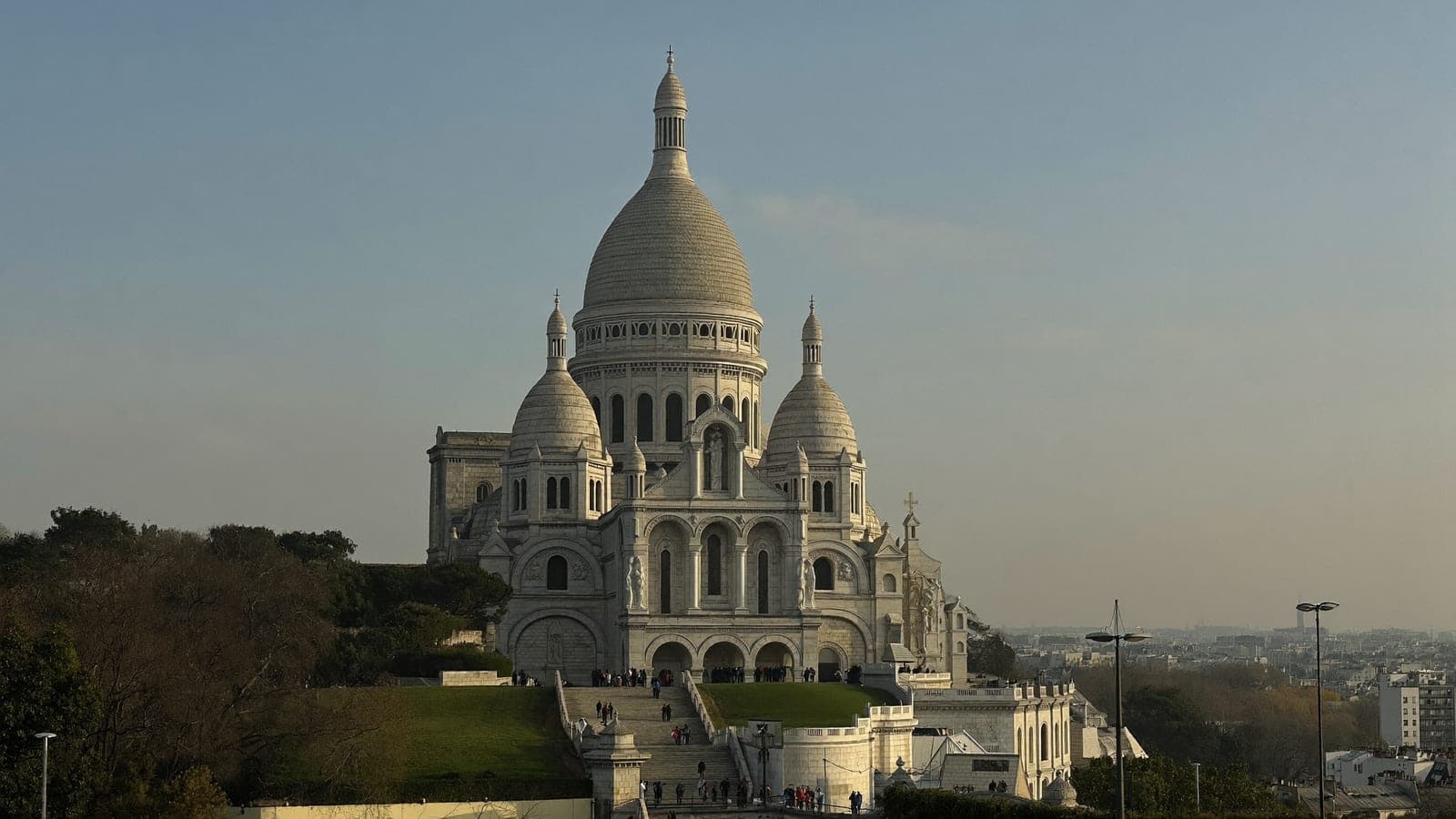 Sacre-Coeur seen from the lawns in late afternoon, the staircase and the rooftops of Paris