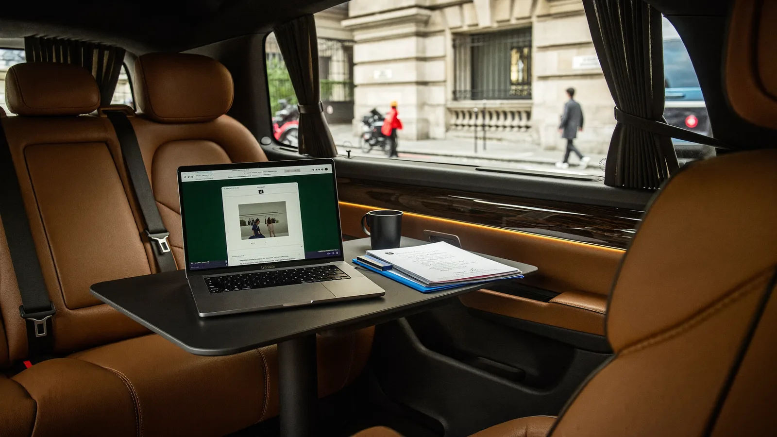 Laptop and documents on the folding table of a chauffeured Mercedes van