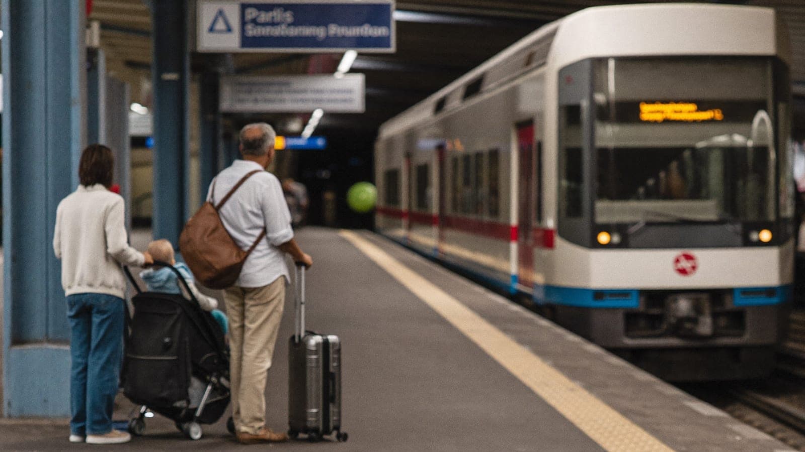 Family with luggage and stroller at Paris RER station platform commuter train Versailles