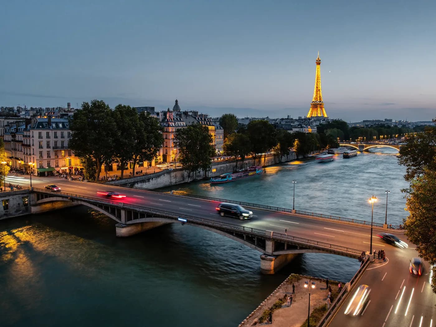 Ponte sobre o Sena e a Torre Eiffel iluminada ao anoitecer